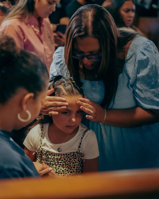 Una niña acompañada en oración durante una reunión de la iglesia